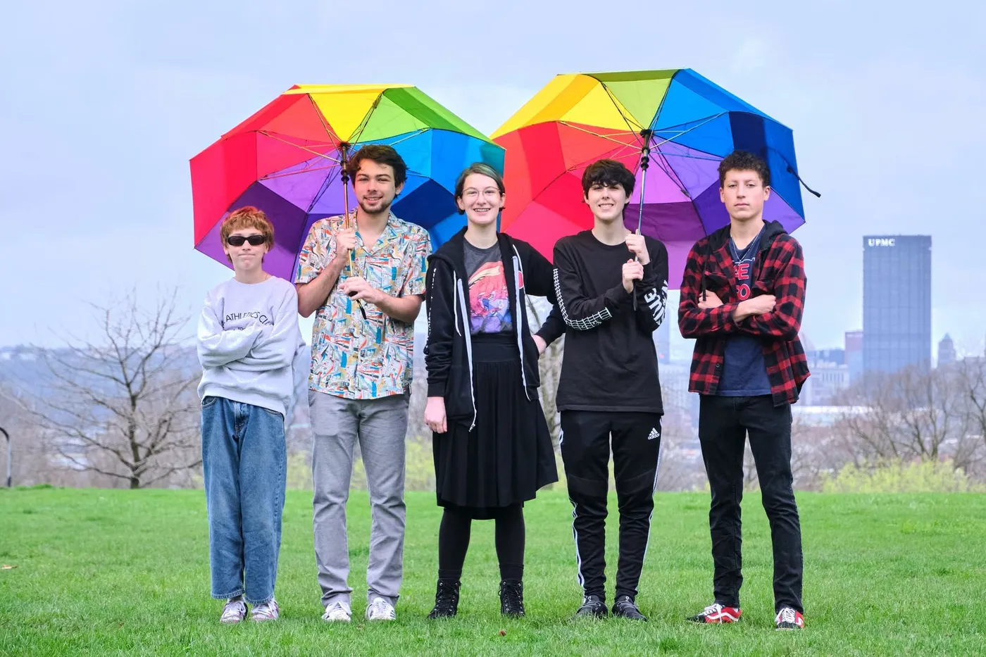 The Sunburst House Band poses with rainbow umbrellas above the Pittsburgh skyline