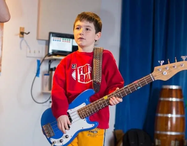 A young bassist plays a red bass during his lesson